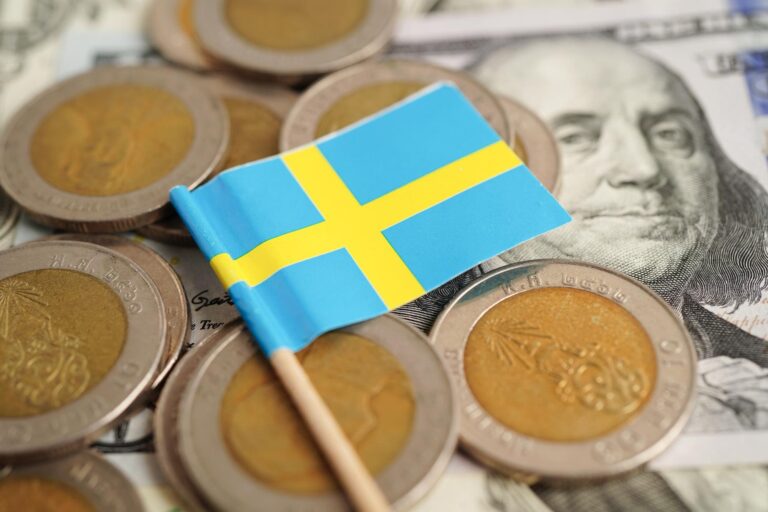 Monety ze szwedzką flagą które symbolizują szwedzkie rozliczenie podatkowe inkomstdeklaration